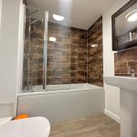Modern bathroom with brown tiled walls and bathtub.