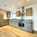 Modern kitchen with wooden cabinets and flooring.