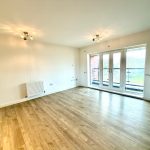 Spacious living room with wooden flooring and balcony view.