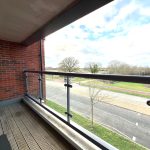 View from balcony over street and trees.