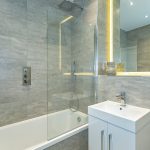 Modern bathroom with sleek grey tiles and shower.