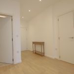 Minimalist hallway with doors and wooden floor.