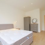 Modern bedroom with bed, wardrobe, and chest of drawers.