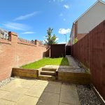 Sunny backyard with brick walls and patio stones.