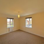 Empty room with carpet and two windows.