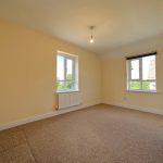 Empty room with two windows and beige walls.