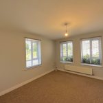 Bright room with three windows and beige carpet.