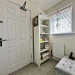 Hallway with door, shelves, window, and telephone.
