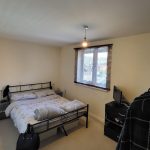 Bright bedroom with double bed and window blinds.