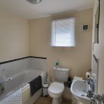 Modern bathroom with tub, toilet, sink.