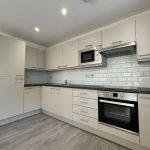 Modern kitchen with white cabinets and appliances.