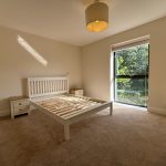 Bright empty bedroom with bed frame and window view.