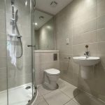 Modern bathroom with shower, toilet, and sink.