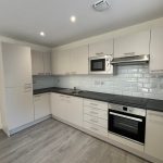 Modern kitchen with white cabinets and appliances.