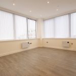 Empty room with large windows and wooden floor.