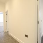 Modern hallway with wooden flooring and open doors.