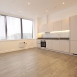 Modern kitchen with wood flooring and large windows.