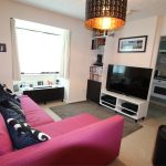 Cosy living room with pink sofa and TV.