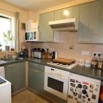Compact kitchen with appliances and green cabinets.