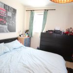 Bedroom with double bed and red bus picture.