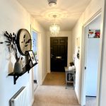 Modern hallway with chandelier and decorative accents.