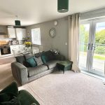 Modern living room with open kitchen and garden view.