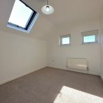 Bright empty room with skylight and radiator.