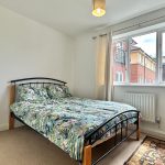 Bright bedroom with floral bedding and window view.