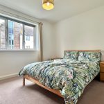 Bright bedroom with double bed and window view.