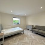 Minimalist bedroom with bed, sofa, and window.