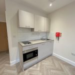 Compact modern kitchen with white cabinets and appliances.