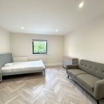 Minimalist bedroom with bed, sofa, and window view.