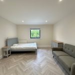 Minimalist bedroom with bed, sofa, and window view.