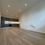 Modern empty kitchen with wooden flooring and spotlights.