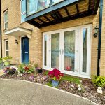 Brick house with blue door and flower garden.