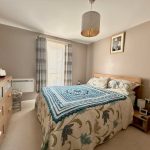 Cosy bedroom with decorative bedspread and window view.