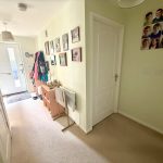 Brightly lit hallway with coat rack and family photos.