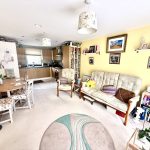 Cosy living room with open kitchen and decor.