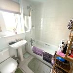 Modern bathroom with white tiles and tub.