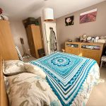 Cosy bedroom with blue patterned bedspread and art.