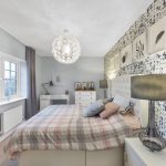 Modern bedroom with patterned wallpaper and bed linens.