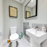 Modern bathroom with sink, toilet, and framed artwork.
