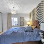 Modern bedroom with patterned wall and blue bedding.