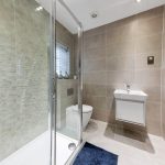 Modern bathroom with shower, sink, and heated towel rail.