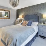 Modern bedroom with stylish decor and large mirror.