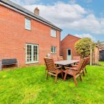 Backyard with table, chairs, and brick house.