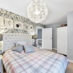 Stylish bedroom with patterned wallpaper and modern lighting.