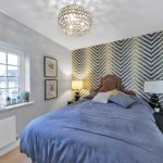 Modern bedroom with geometric wallpaper and blue bedding.