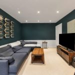 Modern living room with dark green walls and TV.