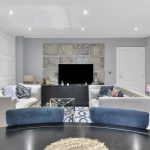 Modern living room with stylish decor and large TV.